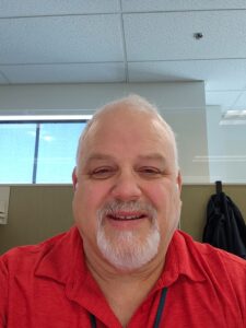 A headshot of Jim Fellows, a middle aged white guy in a red polo shirt.